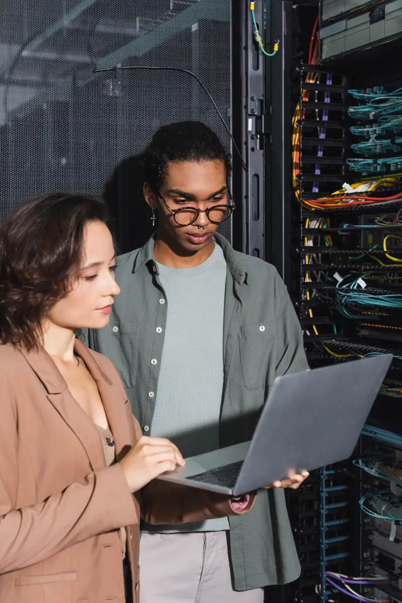 Technicians working on a laptop near server racks